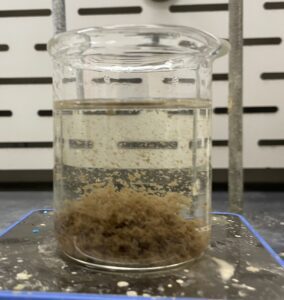 Glass beaker showing solid precipitation formed from EES wastewater treatment chemicals
